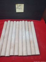 Ten wooden rolling pins laid side-by-side on red surface