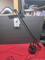 Full view of black adjustable desk lamp showing arms, base and head