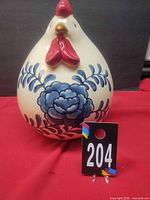 Front view of ceramic chicken showing floral design and scale