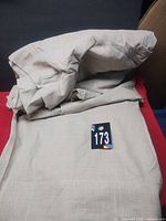 Folded beige curtain material with lot tag visible