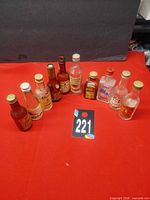 Ten empty miniature liquor bottles on red surface