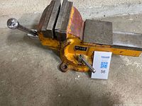 Full view of yellow GMC bench vise showing handle, jaws and base
