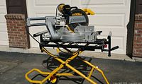 DeWalt DW708 sliding compound miter saw on yellow folding stand, side profile.