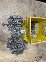Galvanized heavy chain coiled beside yellow crate