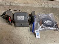 Full view of bench grinder with installed wheels and bagged spare wheel