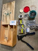 Overview showing rivet gun, sealed packs, bags, tubs of rivets and wooden storage box
