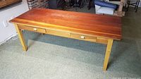 Full view of solid wood table front showing plank top, drawers, legs