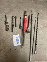 Group of nine assorted drill bits laid out on floor