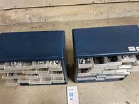 Two blue plastic drawer cabinets filled with assorted hardware