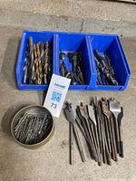Assorted twist and spade drill bits in blue bin and metal tin