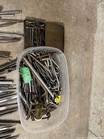 Top view of plastic bin and metal tray filled with assorted steel punches, reamers, taps and wrenches