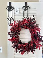 Full view of berry wreath hanging on door with two black metal hangers