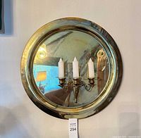 Front view of brass convex mirror with candle sconce