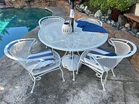 overview of patio table, four chairs, cushions, lantern, umbrella base