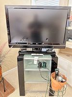 Front view of LG TV on glass stand with headphones and cords visible