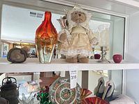 Top shelf with amber glass vase, plush angel bear, stone paperweight, candle holders