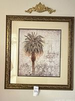 Overall view of framed palm tree print with wall ornament above