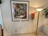 Wall showing framed print, floor lamp, glass vase on shelf