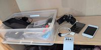 Overview of lot on shelf showing bin of accessories, iPod Classic, iPod Touch, cable and bracket