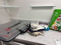 Grey zippered carrying case, fabric totes, blue pompom makers and packaged items on countertop