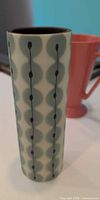 Front view of tall cylindrical vase showing geometric teal circle pattern