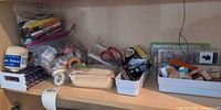 Shelf with mixed scrapbooking supplies in trays and bags