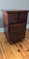 front view of dark wood side table showing four drawers and knobs
