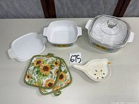 All items laid out: two dishes, lid, potholders, spoon rest