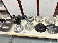 All thirteen aluminum bundt and novelty pans laid out on table showing variety of shapes and finishes