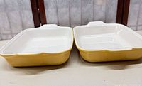 Top view of both yellow exterior, white interior rectangular casserole dishes