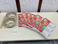 Lot overview with six packaged Wilton cookie pans and Nordic Ware pumpkin pan