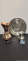 Overall view of three items: copper inlaid vase, pewter plate, pewter bud vase