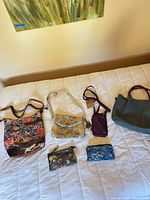 All six bags and wallets laid out on bed