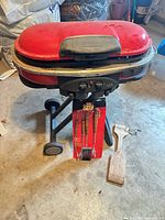 Closed Coleman RoadTrip grill on cart with tool set and wooden spatula visible