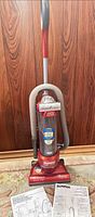 Full view of Eureka upright vacuum with hose and manuals
