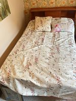 Bed made with floral comforter and square pillow