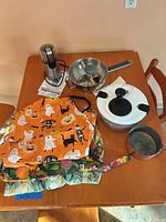Aprons, salad spinner, food mill, KitchenAid grinder, saucepan grouped on table