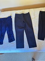 three pairs of navy and dark pants laid flat on bed