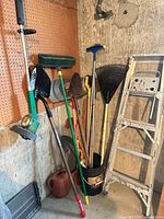 Group shot of all tools leaning against wall with ladder visible