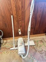 Full view of vacuum canister with hose, wand and floor head on rug