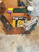 overall view showing wooden trunk, saw, kneeling pads, cords and hose