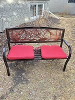 Front view of metal bench with red cushions outdoors