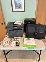 Overall lot on table: printer, shredder, bag, paper, cables, manuals