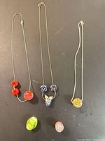 Overall lot showing three necklaces and two loose beads on black surface