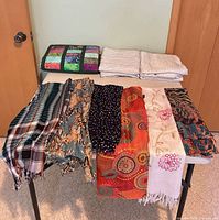 Overall lot: folded patchwork quilt, stacked beige curtain panels, seven scarves displayed