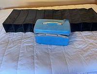 Blue makeup case closed, black hanging organizer folded beside