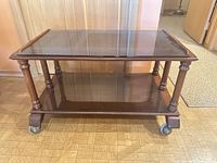 Front view of mahogany two-tier bar cart showing glass top, wood shelf, casters