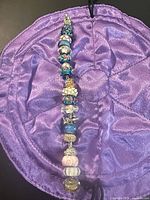 Full view of bracelet laid flat on purple pouch showing all beads and lobster clasp