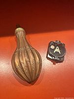 Powder flask and closed compass side by side