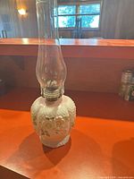 Front view of white oil lamp with clear chimney